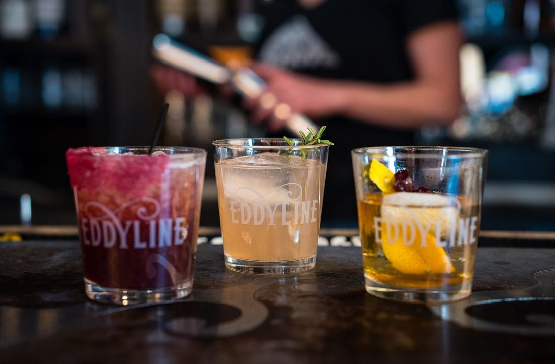 Three cocktails in Eddyline glasses on the bar
